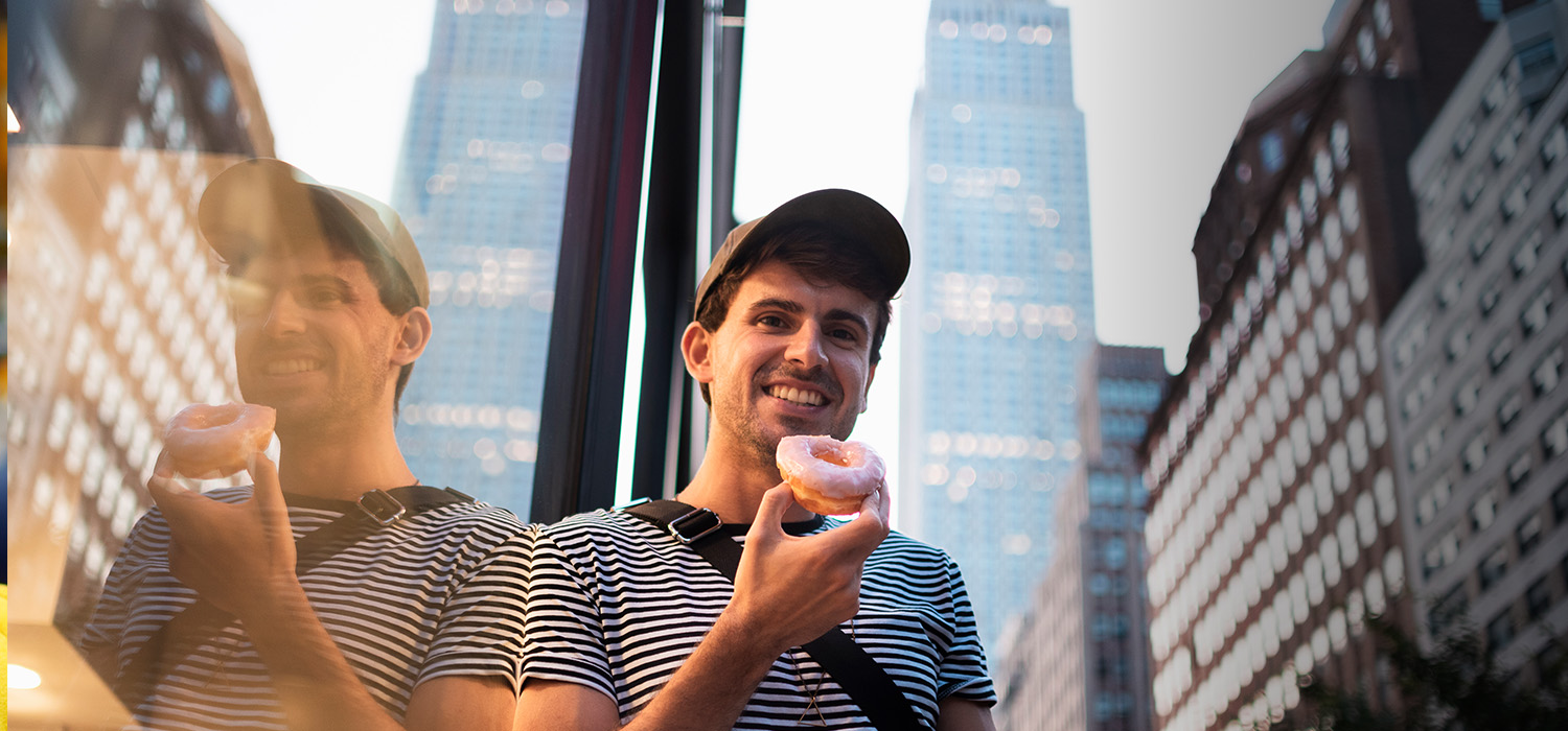 Young man eating a donut in the center os New York