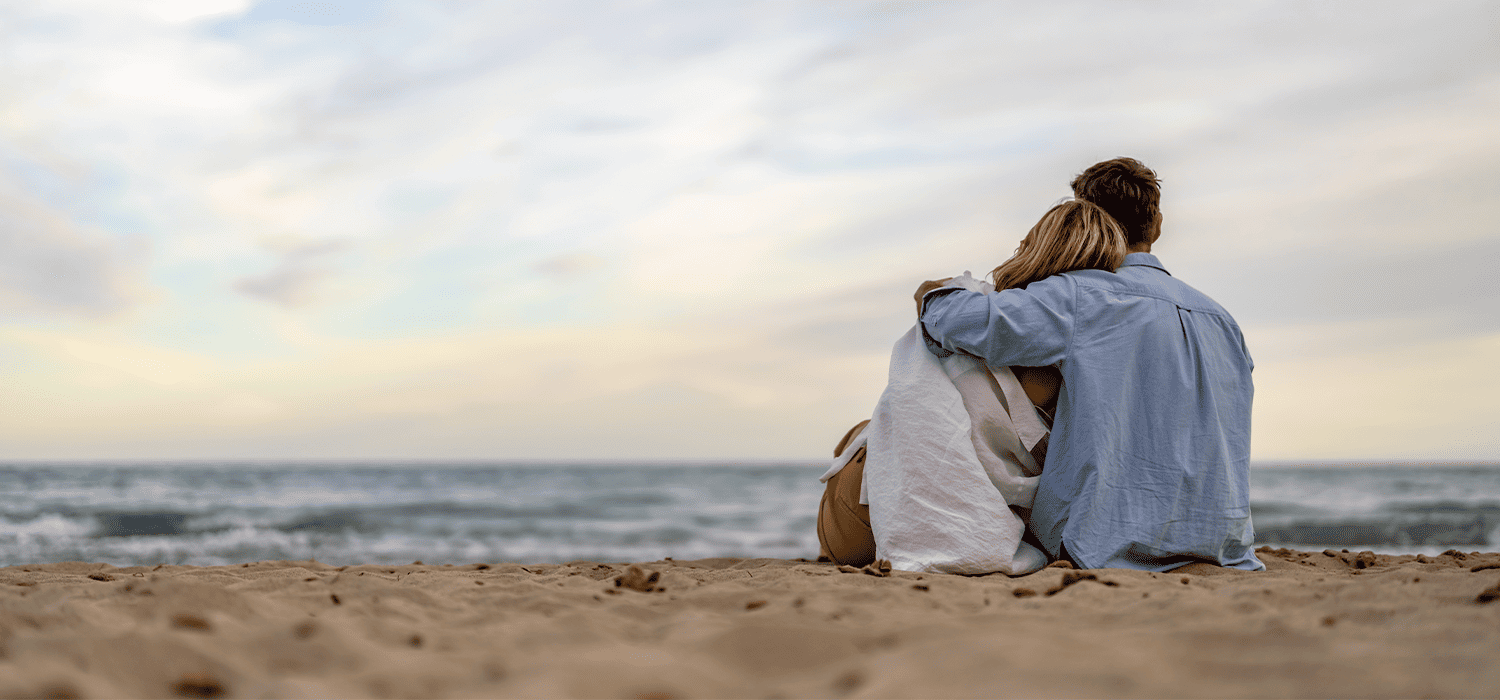 Couple sitting on the sand watching the sea