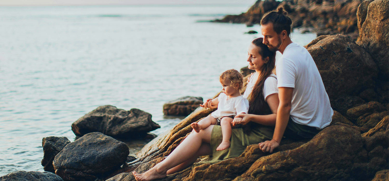 Família sentada à beira mar.