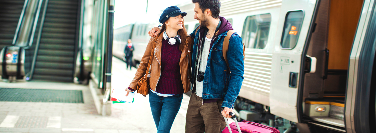 Casal turista numa estação de comboio. Rail & Fly